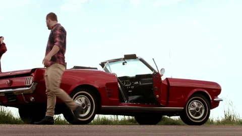 Couple have broken down, due to no gas/ fuel while driving a classic cherry red Stock Footage 199632084
