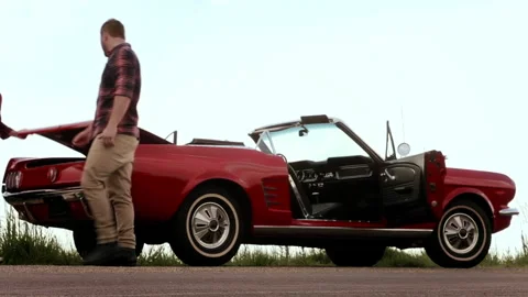 Couple have broken down, due to no gas/ fuel while driving a classic cherry red Stock Footage 199632431
