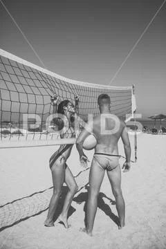 Couple have fun playing volleyball. Young sporty active couple stand near Stock Photos