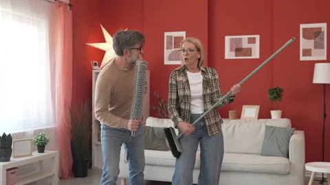 Couple have fun while clean living room use broom like electric guitar Stock-Footage 303993631