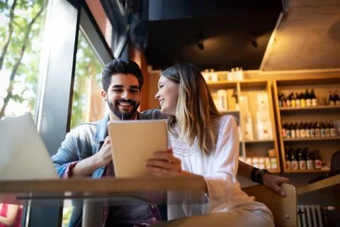 Couple have fun while looking on laptop at cafe Stock Photos