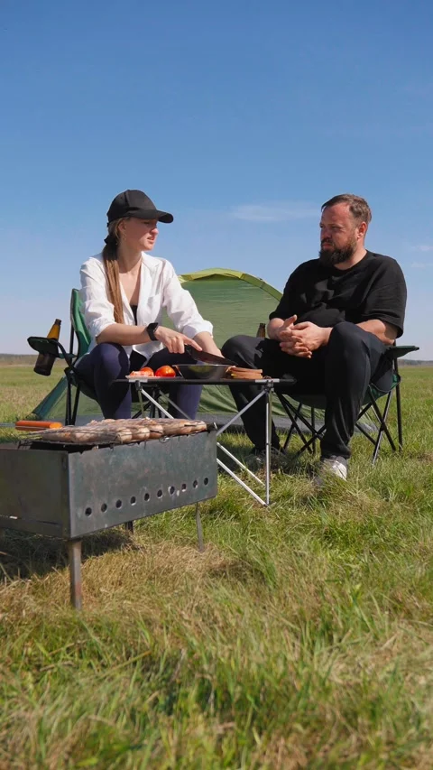 Couple having barbecue while camping outdoors Видео 344606457