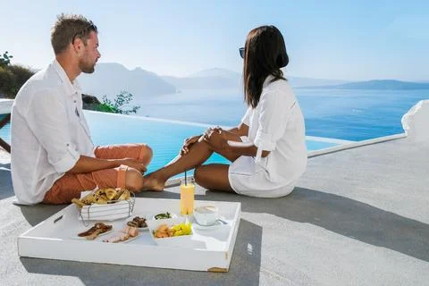 Couple having breakfast by the infinity pool looking out over the Caldera ocean Fotos Stock