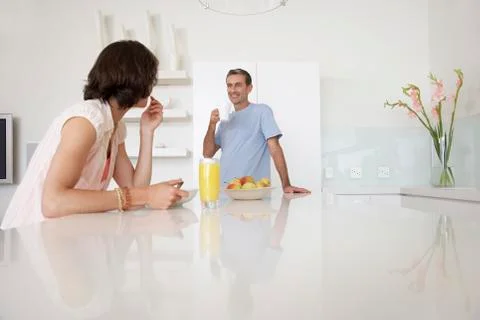 Couple Having Breakfast At Kitchen Bench Stock Photos