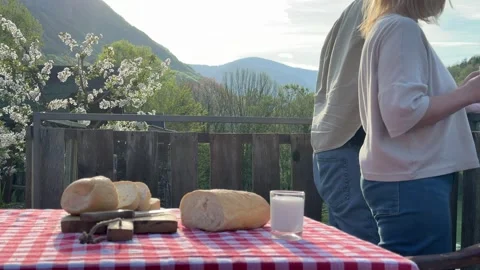 Couple having breakfast outdoors on rustic terrace with bread and milk Stock Footage 333525939