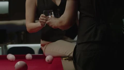 Couple is having a conversation in a bar, seated on the edge of a pool table. Stock-Footage 278983157