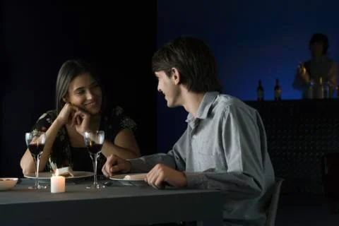 Couple having conversation over dinner at restaurant, smiling at each other Fotos Stock