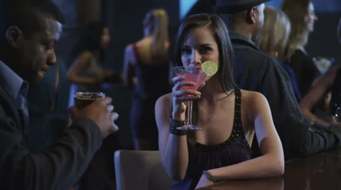 A couple having a drink at a bar, with the young woman looking into camera Stock Footage 34005983