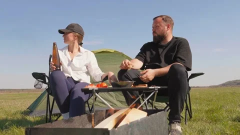 Couple having fun and drinking beer at campsite Stockbeeldmateriaal 344606734