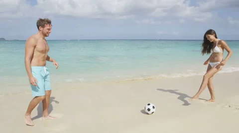 Couple having fun on beach playing soccer football - summer vacation travel Video stock 46955332