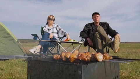 Couple having fun camping while grilling meat on barbecue Stock Footage 319791492