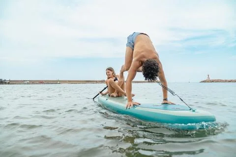 Couple having fun doing handstand on paddle board Stock Photos