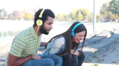 Couple having fun listening to music on headphones at the park Stock Footage 59555016