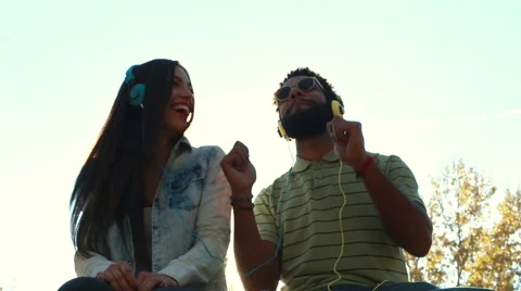 Couple having fun listening to music with headphones on sunny day Stock Footage 59555416