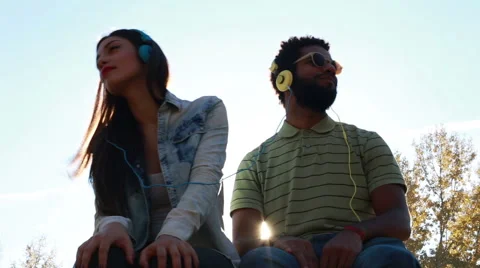 Couple having fun listening to music with headphones on sunny day Stock Footage 59555432