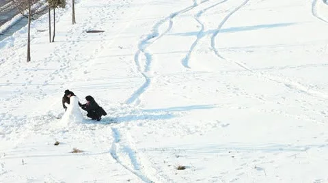 Couple having fun making a snowman in snow outdoors. Stock Footage 10740990