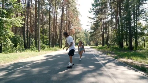 Couple having fun with skate on an empty road Stock Footage 99678543