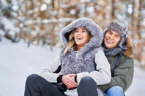Couple having fun with sledge on snow in winter Stock Photos