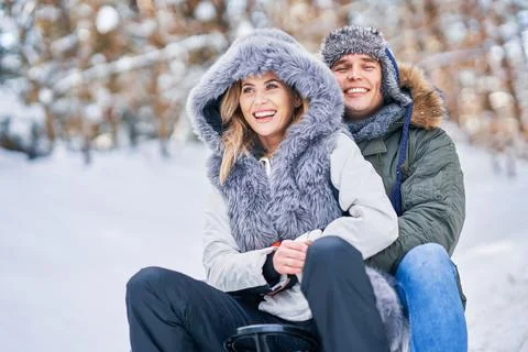 Couple having fun with sledge on snow in winter Stock Photos