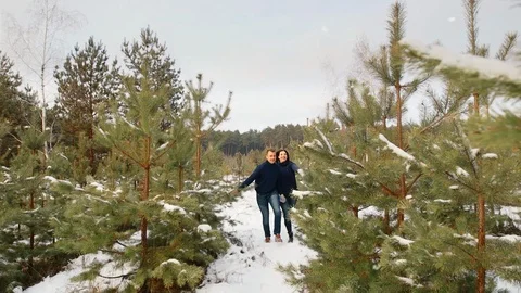 Couple having fun in the winter forest. They run through the snow and laugh. The Vídeos de archivo 99923686