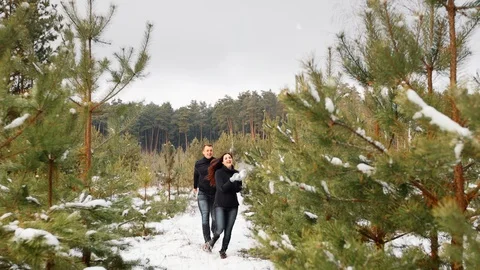 Couple having fun in the winter forest. They run through the snow and laugh. The Stock Footage 99924181