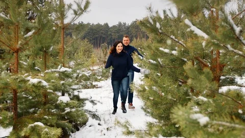 Couple having fun in the winter forest. They run through the snow and laugh. The Vídeos de archivo 100017400