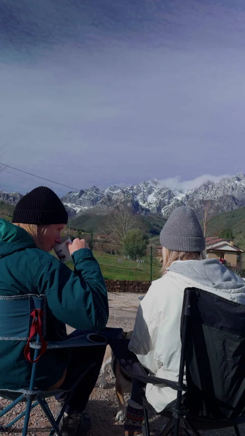 Couple having meal outside campervan overlooking snowy mountain landscape Stock Footage 336632306