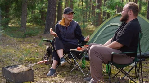 Couple having picnic while camping in pine forest Видео 327136793