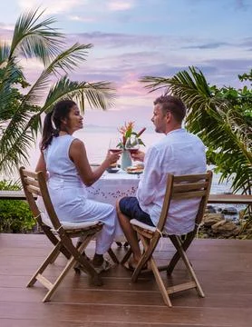 Couple having romantic dinner, dinner table looking out over ocean with Thai Fotos Stock