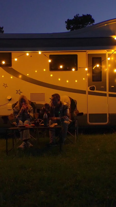 Couple having romantic dinner outside camper van at night Видео 345751075