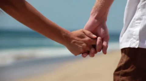 Couple on Hawaiian beach hold hands and walk away from the camera Stock Footage