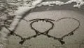 Couple of heart. A wave removes one heart drawn in the sand; the end of a love HD Footage