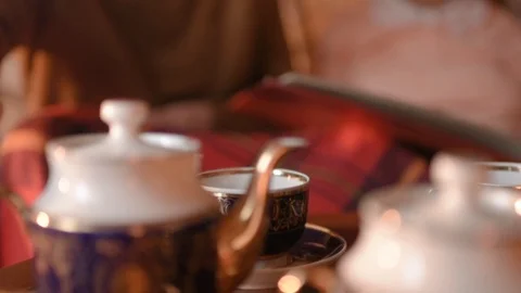 The couple hiding behind a blanket drinking tea and looking photo Stock-Footage 99257334