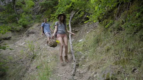 Couple Hike Down Steep Slope In Forest, Woman Carries Basket Of Wild Flowers Stock Footage 68355184