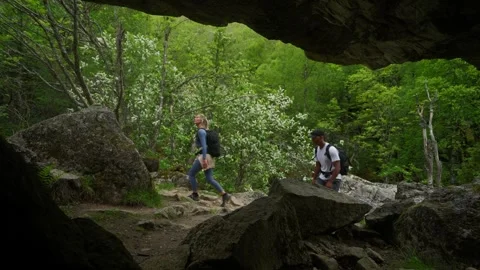 Couple Hikers Camera Framing from Cave Walking Through Dense Forest 動画素材 333843819