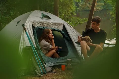 Couple of hikers camping in forest on their weekend Stock Photos