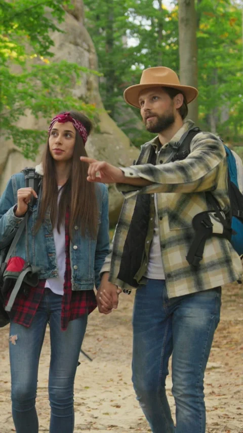 A couple hikes through a lush forest, holding hands and sharing joyful moments Vídeo Stock 316514562