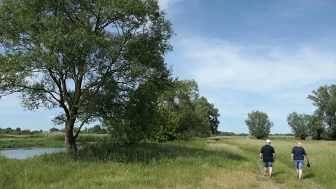 Couple hiking along a small path through meadows of Havel river landscape in  스톡 동영상 109749239