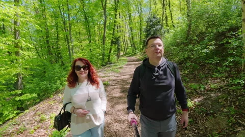 Couple hiking through green forest during sunny spring day Stock Footage 345582459