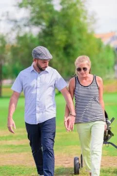 Couple hold hands while having a walk at the park Stock Photos