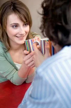 Couple holding cups, face to face, looking at each other Stock Photos