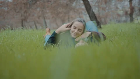 Couple holding each other while lying on grass in a forest Stock Footage 275276752