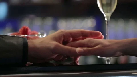 Couple holding each others hand with champagne at the back Stock Footage 71782776