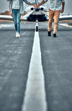 Couple holding hand while walking on runway Stock Photos