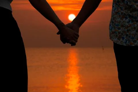 Couple holding hands and blurry beautiful sunset Stock Photos