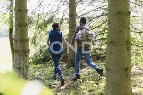 Couple holding hands and hiking with backpack in woods Stock Photos