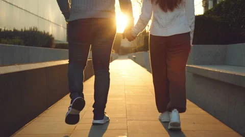 A couple holding hands and walking away toward the sunset in the golden hour. Stock Footage 146501866