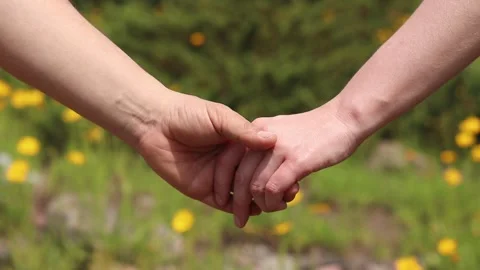 Couple holding hands on a background of a meadow with yellow flowers Stock Footage 336906902