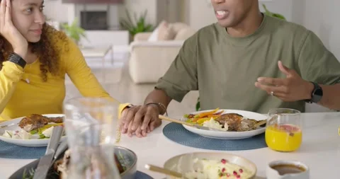 Couple holding hands at dining table while African American man speaking, 스톡 동영상 337254712