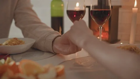 Couple holding hands during candlelit dinner, one giving thumbs-up beside red Stock Footage 346645914